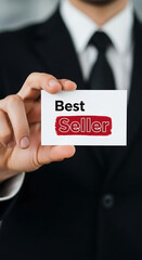 Obraz premium Man in Black Suit Holding Best Seller Card Red Text