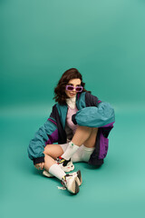 Stylish young woman showcasing trendy sporty outfit against vibrant turquoise background