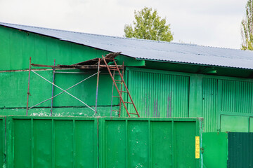 Vibrant green building juxtaposed with a rusty ladder under a bright sky
