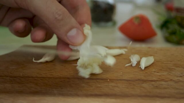 The man crushes the garlic with a knife and releases it from the shell. Close-up