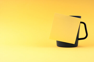 Blank sticky paper note on a glass with yellow background