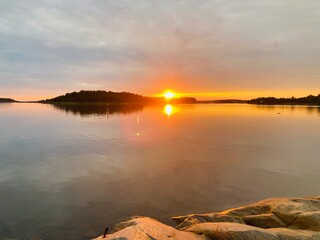 Golden Sunset Over Lake, Water Reflections and Rocky Shoreline

