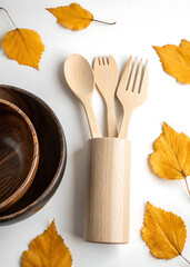 Natural wooden cutlery set with autumn leaves and rustic bowls for a seasonal table setting