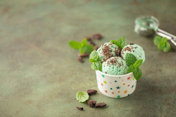 Mint chocolate ice cream balls  in paper bowl on green background