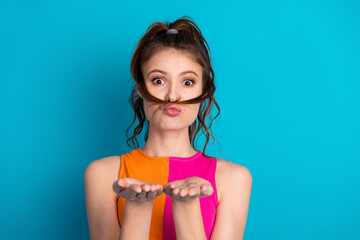 Playful young woman with vibrant style posing against a bright blue background, exuding charm and...