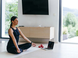 Young Beautiful Female Exercising, Stretching and Practising Yoga with Trainer via Video Call Conference in Bright Sunny House. Healthy Lifestyle, Wellbeing and Mindfulness Concept.
