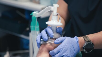 An anesthesiologist holding an anesthesia mask on a patient’s face. Concept patient care and safe anesthesia administration. - Powered by Adobe