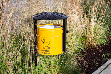 Yellow Dog Waste Bin with Polish Text in Ornamental Grass   Żółty kosz na psie odchody z grafiką psa i napisem "Posprzątaj po mnie"  © Adrian White