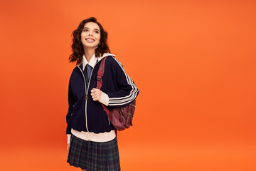 Stylish young woman poses with confidence in vibrant orange studio