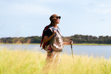Beautiful woman in hiking outfit standing by the lake and nature in morning.