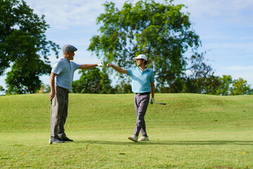 Asian man and elderly father are enjoy playing golf together with a good time.