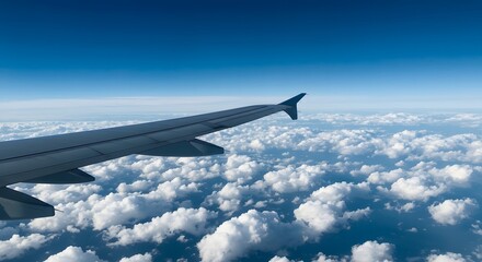 Fototapeta premium Airplane wing above a sea of fluffy white clouds