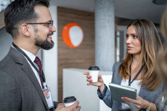 Business people talking and holding coffee cups at conference - Powered by Adobe