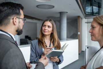 Businesswoman holding notebook talking to colleagues during coffee break