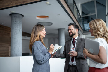 Businesspeople talking and smiling during a coffee break in the office hall