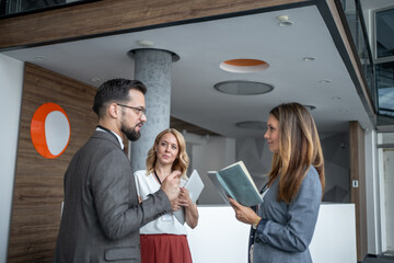 Businesspeople discussing work in modern office lobby