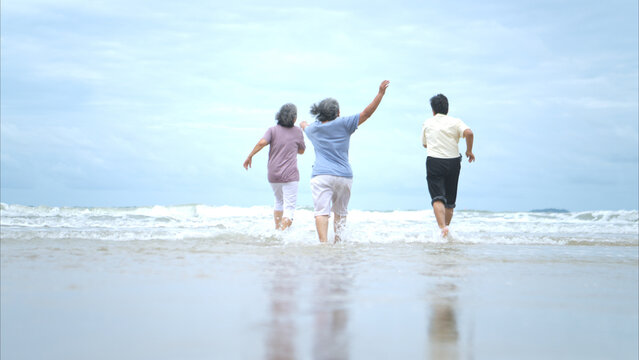 Happy senior women enjoying a playful walk on the beach,
