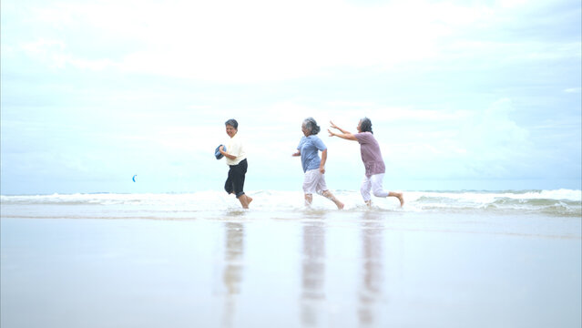 Happy senior women enjoying a playful walk on the beach, - Powered by Adobe