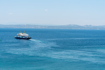 Ferry navigates through calm blue waters with distant hills under a clear sky