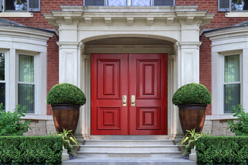 Elegant portico entrance of home with maroon colored front door and bay windows