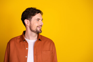 Portrait of a smiling young man with stylish brown shirt against vibrant yellow background...