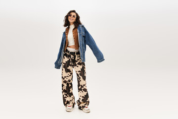 Fototapeta premium Trendy young woman showcases stylish cow print pants in modern studio setting