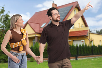 Happy couple near their house outdoors. Real estate ownership