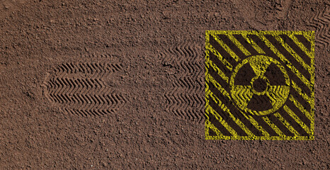 Yellow radioactive sign on brown ground with shoes tracks, top view. Radiological pollution