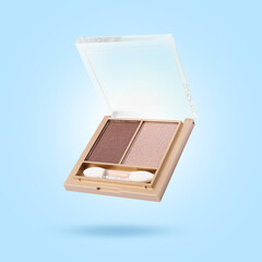 Eyeshadow and applicator in air against light blue background. Makeup cosmetics