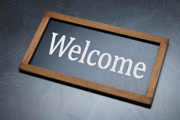 Small chalkboard with word Welcome on black background