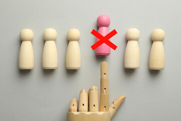 Dismissal. Mannequin hand throwing pink human figure with red cross away on grey background, top...