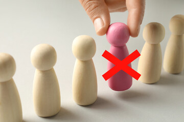 Dismissal. Woman taking pink human figure with red cross away on light background, closeup