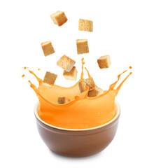 Croutons falling into bowl of soup against white background