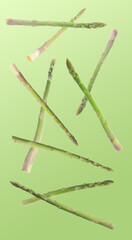 Fresh asparagus falling on green gradient background