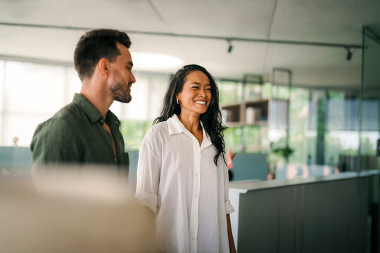 Diverse team of two business people working talking using tablet tech walking in corporate office.