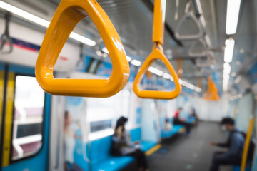 Close-up of yellow hand straps inside a modern train carriage, designed for standing passengers, showcasing urban public transportation and safety in mass rapid transit