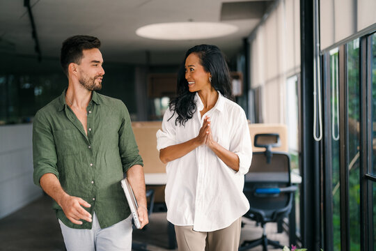 Two happy diverse multiethnic business team people working, talking in corporate office