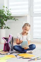 Kid reading notebook while sitting on floor. Back to school.