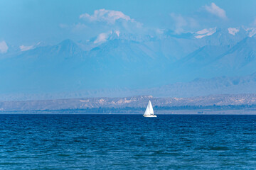 A white sailing yacht sails on the blue lake against the backdrop of majestic multicolored...