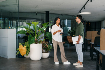 Two happy diverse multiethnic business team people working, talking in corporate office