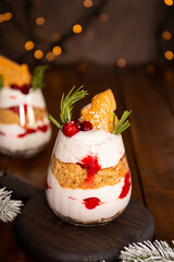 A glass of Christmas dessert with gingerbread cookies, whipped cream and cranberries vertical photo
