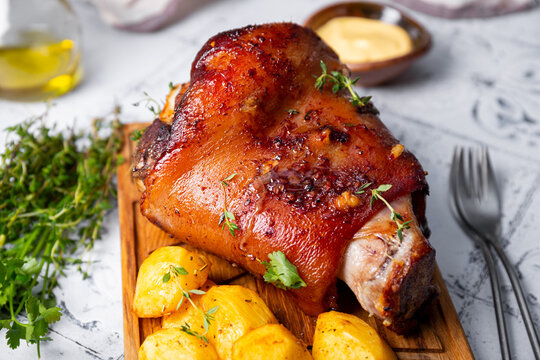 Baked pork knuckle with potatoes and cheese sauce close up