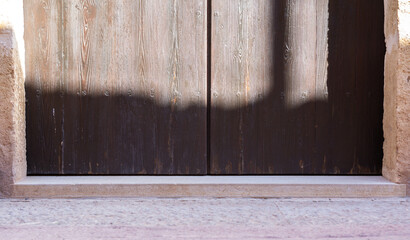 The door is made of wood and has a shadow on it