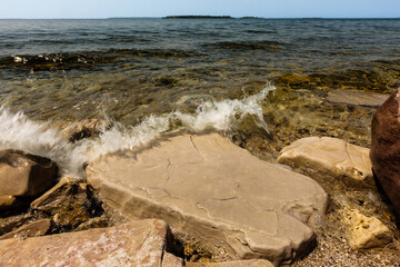 The waves of Green Bay wash over the shoreline rocks along Peninsula State Park, Fish Creek, Door County, Wisconsin in late May