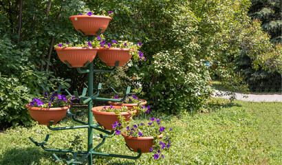 A beautiful multi-tiered metal stand for flower pots, in a park, outdoors