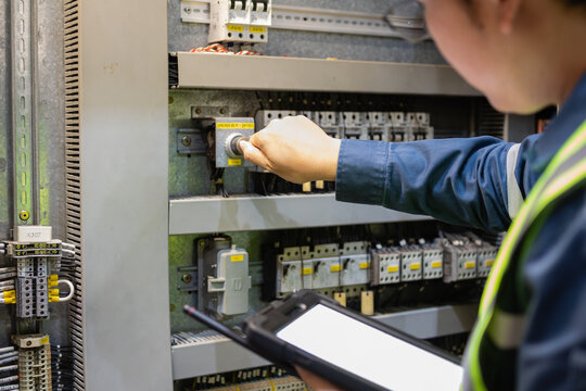 Technician operates switchgear panel in power station ensuring insulated gas components function safely and efficiently during maintenance work