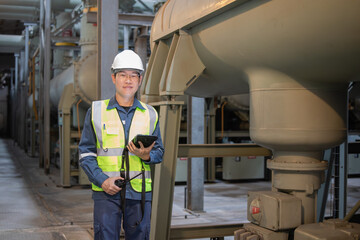 Worker wearing safety helmet and insulated vest operates switchgear equipment in power station with...