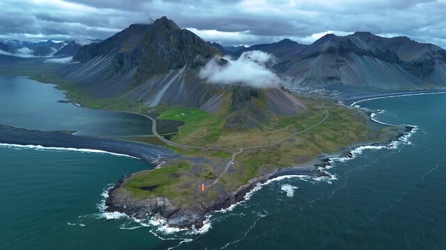 Explore the breathtaking beauty of Icelands rugged coastline with towering mountains and lush greenery. This stunning location showcases natures raw power and tranquility, Hvalnes mountain iceland.