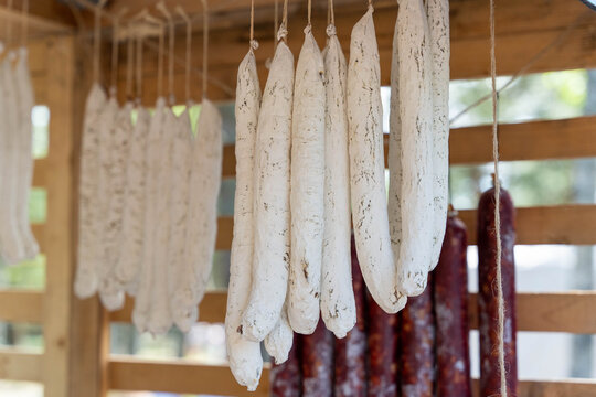 Cured sausages hanging and drying in a wooden smokehouse