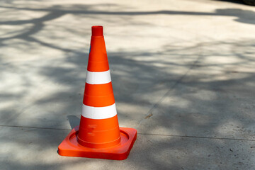 Bright orange traffic cone standing on concrete surface